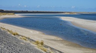 Coastal lagoon surrounded by sandy sediment. A measuring device is operating in the middle of the lagoon.