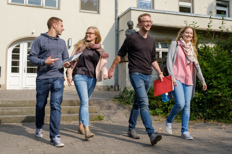 Four students walking in front of the Carolinenhaus in Marburg