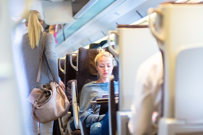 A young woman works on her laptop on the train.